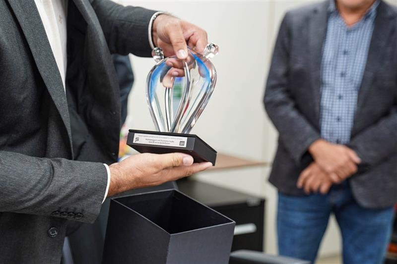 Na primeira imagem vemos o troféu entregue pela Softplan ao DER-DF em reconhecimento à transformação digital da gestão rodoviária e evolução da solução SIDER.